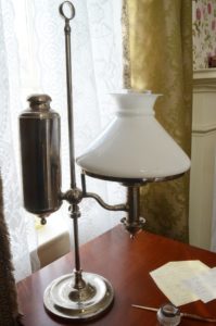 a lamp and preserved examples of Dickinson's writing on her desk