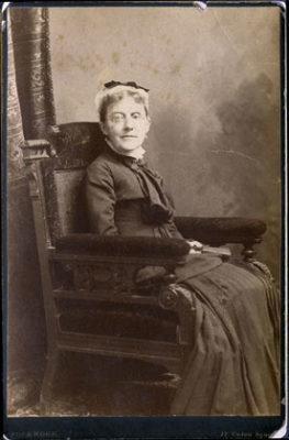 black and white photograph of a seated woman wearing spectacles