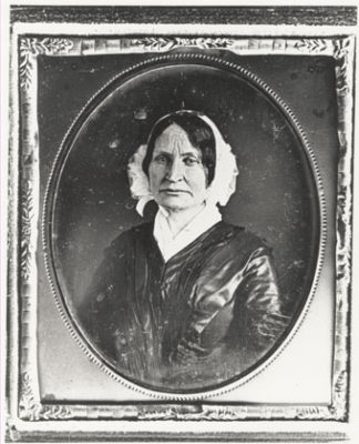 black and white photograph of a woman wearing a white bonnet