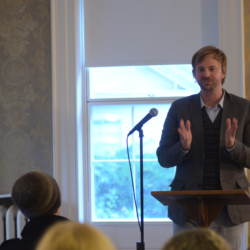 Poet reading at a microphone in the museum