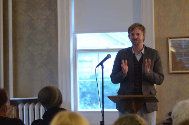 Poet reading at a microphone in the museum