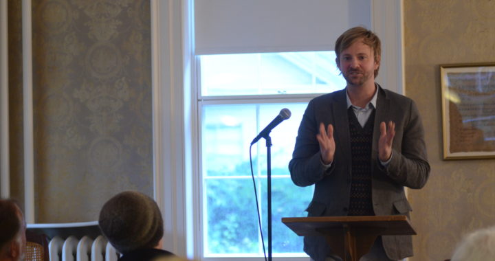 Poet reading at a microphone in the museum