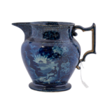 Blue Staffordshire ceramic transferware pitcher with blue glaze showing a scene of a man sitting across from a monument with the name "Franklin" at the base with a tall ship in the distance, known as "Lafayette at Franklin's tomb".