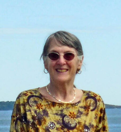 A photo of author Kathryn Holzman in front of an ocean vista