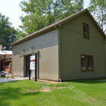 A woman walks into the recently completed carriage house on a sunny day