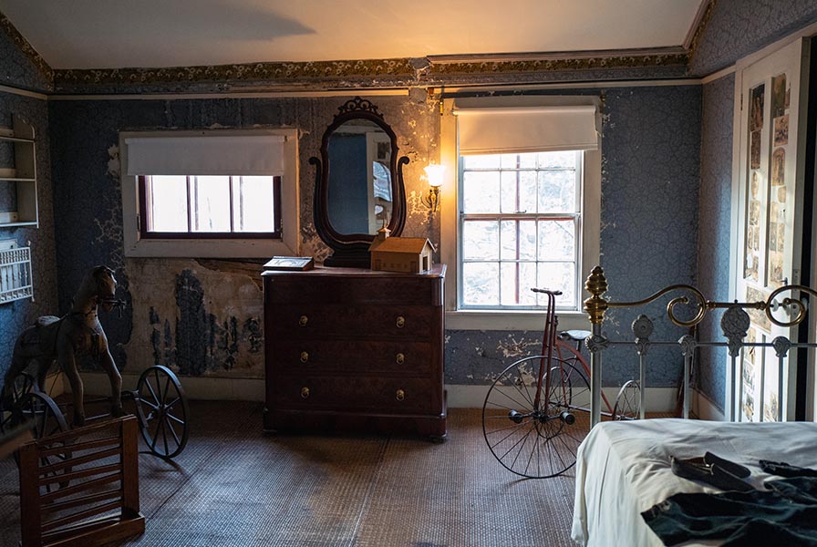 Nursery with many worn toys, including a horse tricycle, marble run, and velocipede.