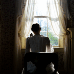 Emily Dickinson at her writing desk with her back to the camera