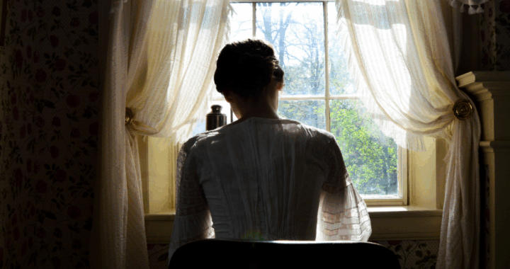 Emily Dickinson at her writing desk with her back to the camera
