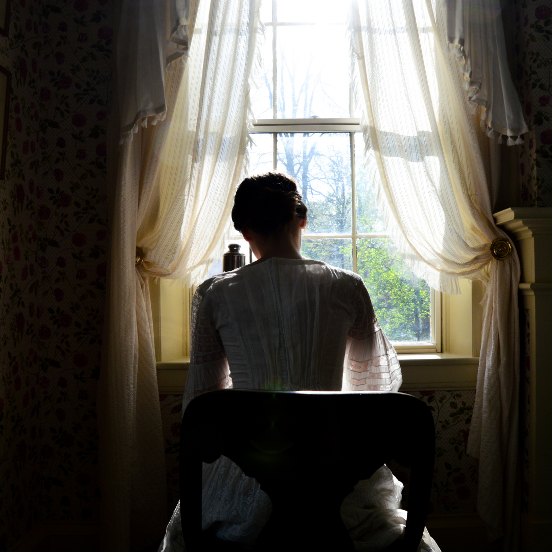 Emily Dickinson at her writing desk with her back to the camera