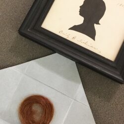 a framed silhouette of emily dickinson as a child and a lock of her bright red hair