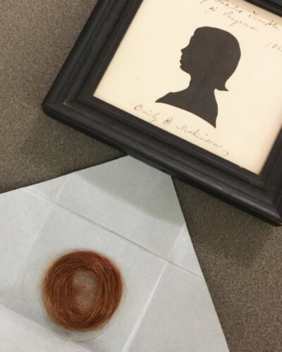 a framed silhouette of emily dickinson as a child and a lock of her bright red hair