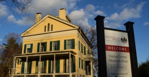 Emily Dickinson homestead painted yellow with a sign in front saying visitor center, museum shop