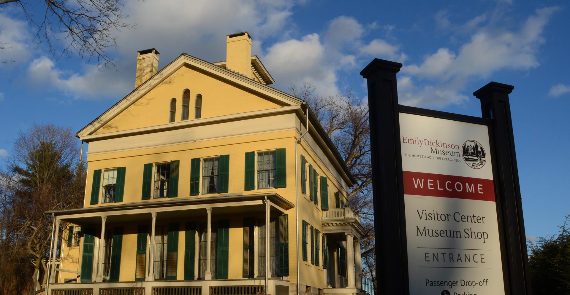 Emily Dickinson homestead painted yellow with a sign in front saying visitor center, museum shop