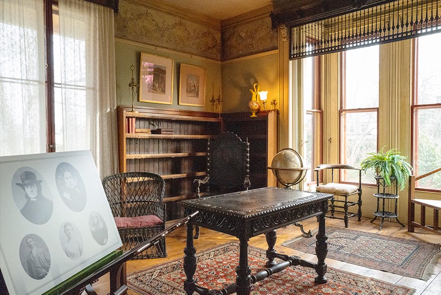 Richly furnished library, with Moroccan carpets, floor globe, and ornately carved library table