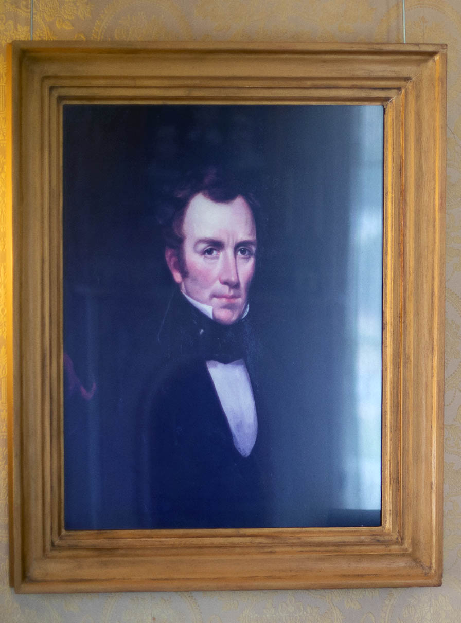 Oil portrait of a stern young man with pale skin, auburn hair, high collar, and necktie.  