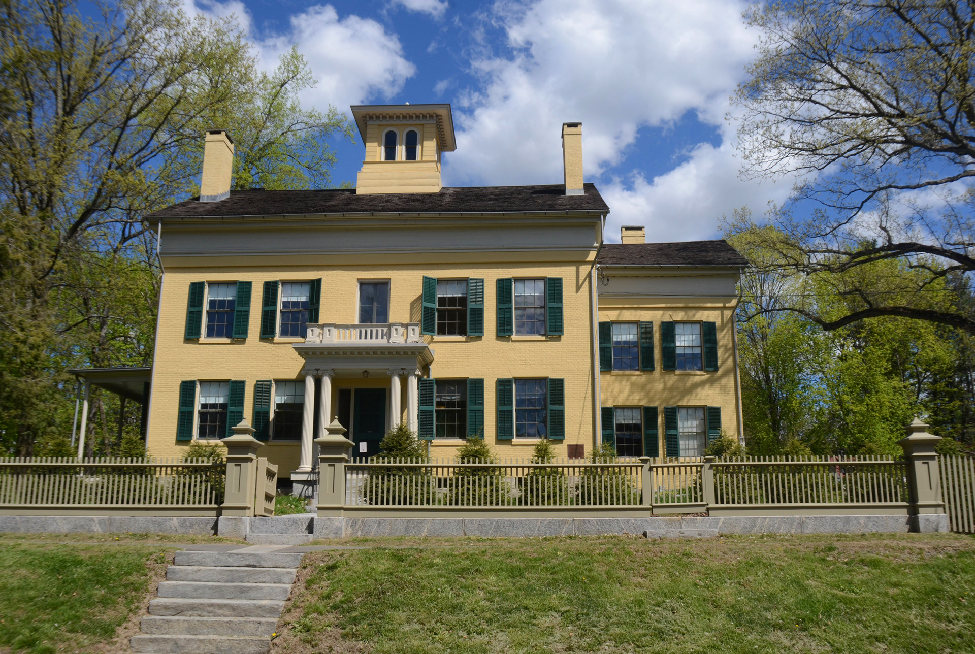 Front of the Dickenson house, which is yelllow, with stone steps