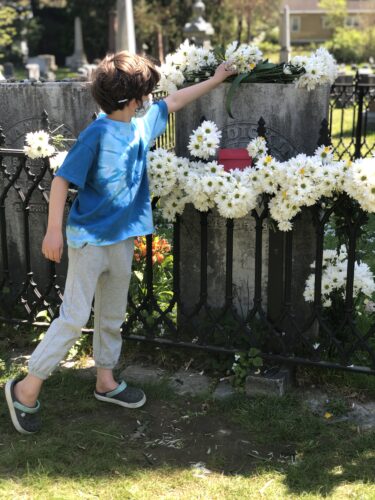a boy places a daisy on Dickinson's grave