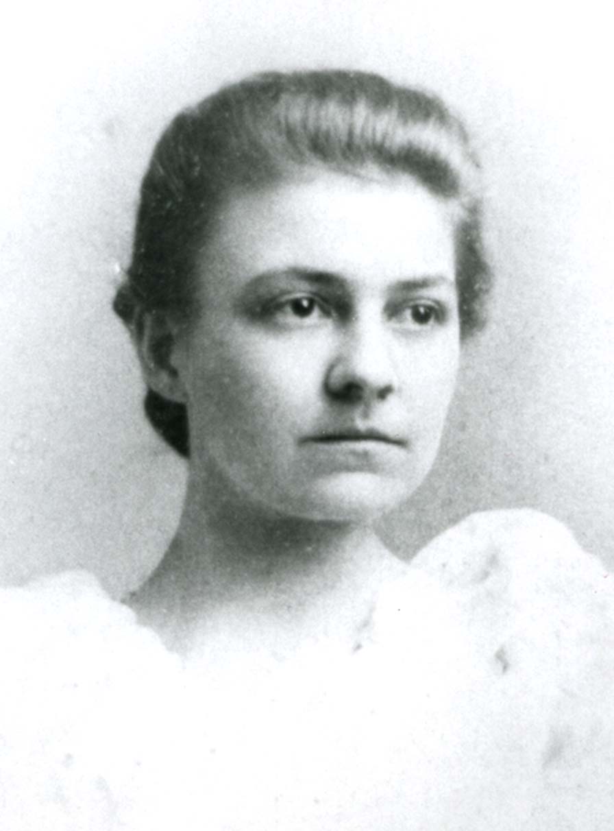 A young woman with her hair pinned up. She has a white dress with puffed sleeves