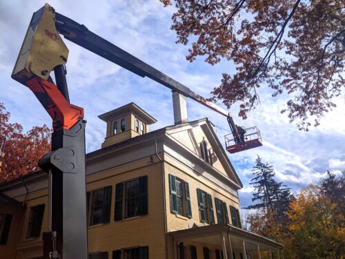 A crane lifts a painter up to the top of the Homestead