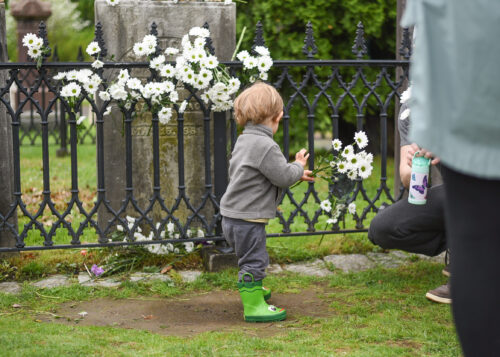 a young kid places a daisy at Dickinson's grave