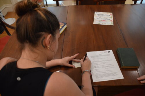 a person signs a donation agreement for the replenishing the shelves project
