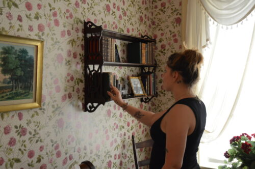 a person places a book on the shelf next to Dickinson's bedroom