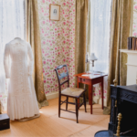 Image of Dickinson's room featuring her writing desk and white dress