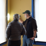 two people are looking into a square cutout carved out of the plaster of the walls at the Dickinson Homestead