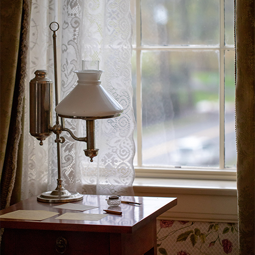 image of a small desk with lamp in front of a paned window