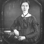 Emily Dickinson daguerreotype, showing the poet seated and facing the viewer, resting one arm on a desk