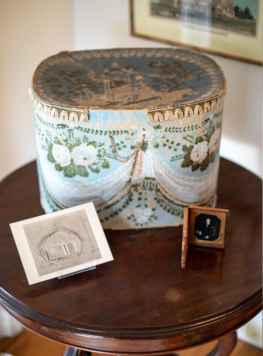 On a small round table sits a decorative cardboard box and lid, behind it an image of the Capitol.