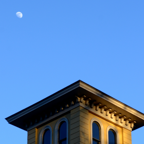The cupola of the Homestead with the moon appearing during clear sky daylight