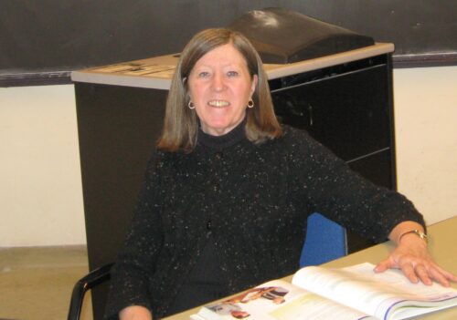 Eileen P. Kennedy is pictured sitting at a table in front of an open book