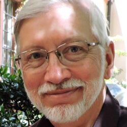 headshot of a man with white hair, mustache, beard and glasses