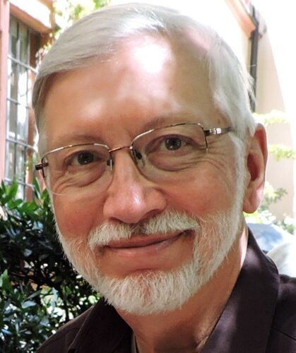 headshot of a man with white hair, mustache, beard and glasses