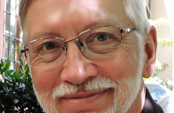 headshot of a man with white hair, mustache, beard and glasses