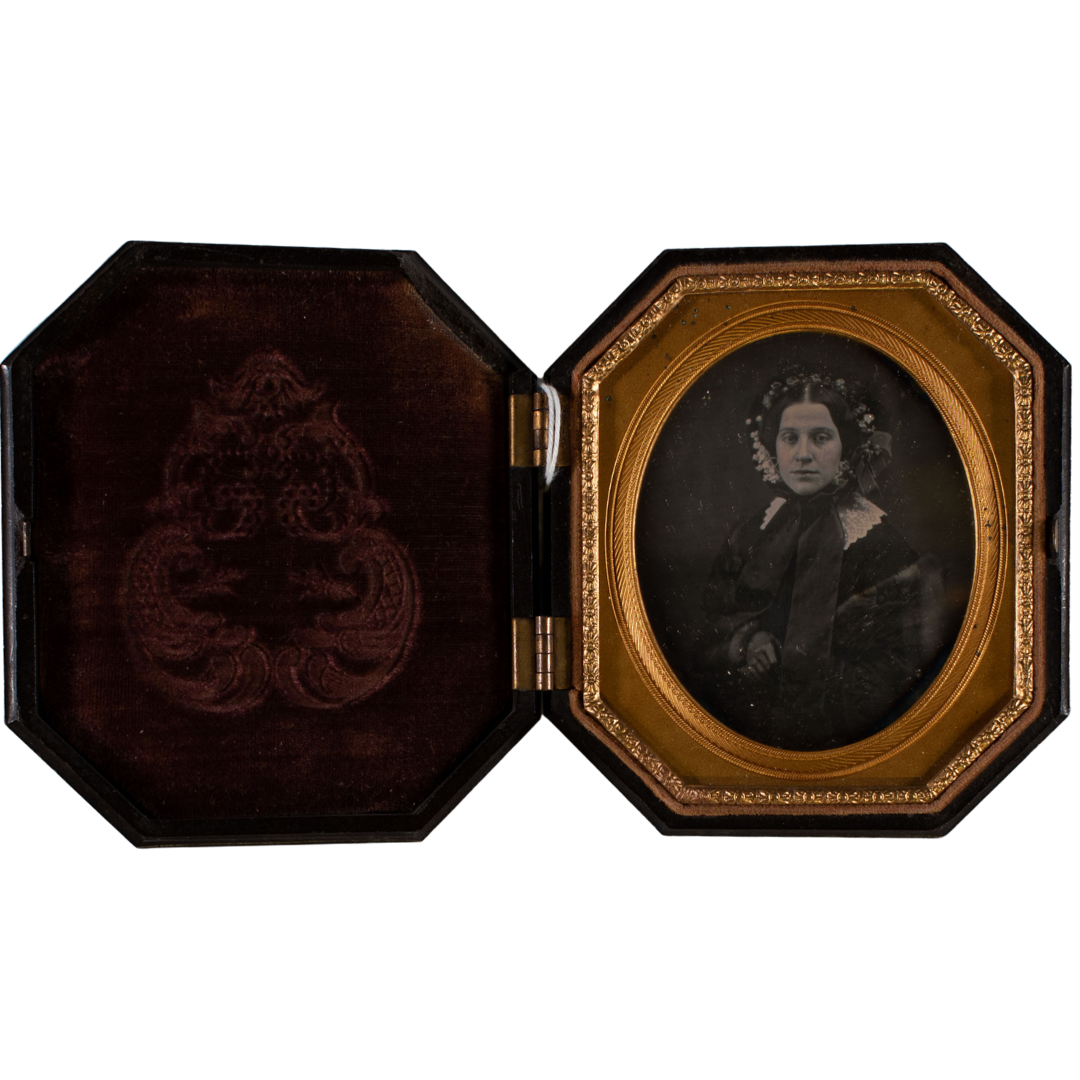 A photo of a women in 19th century clothing in a decorative gold rimmed locket.