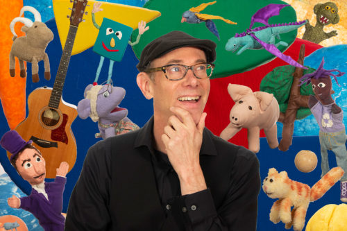 Tom Knight surrounded by puppets