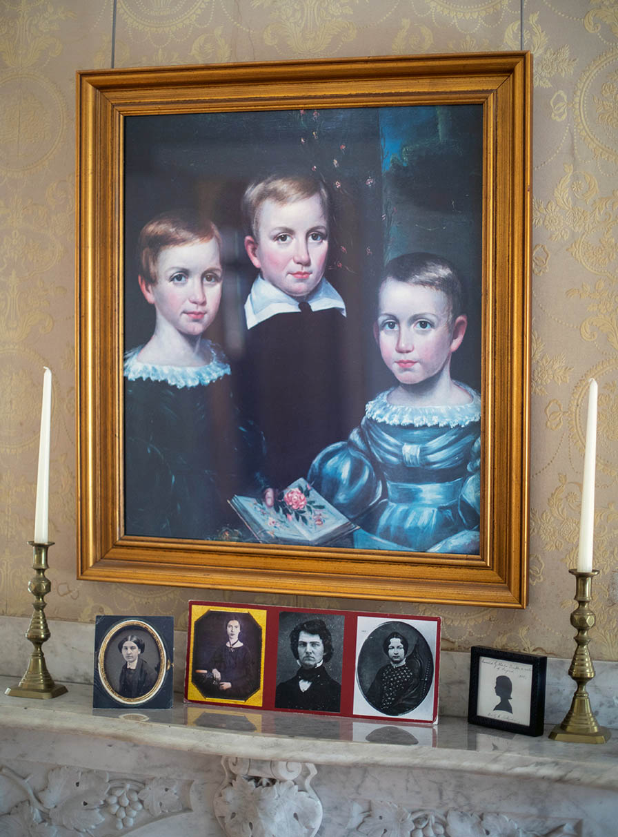 Oil portrait of three young children with short hair gazing out. Emily at left with red hair.